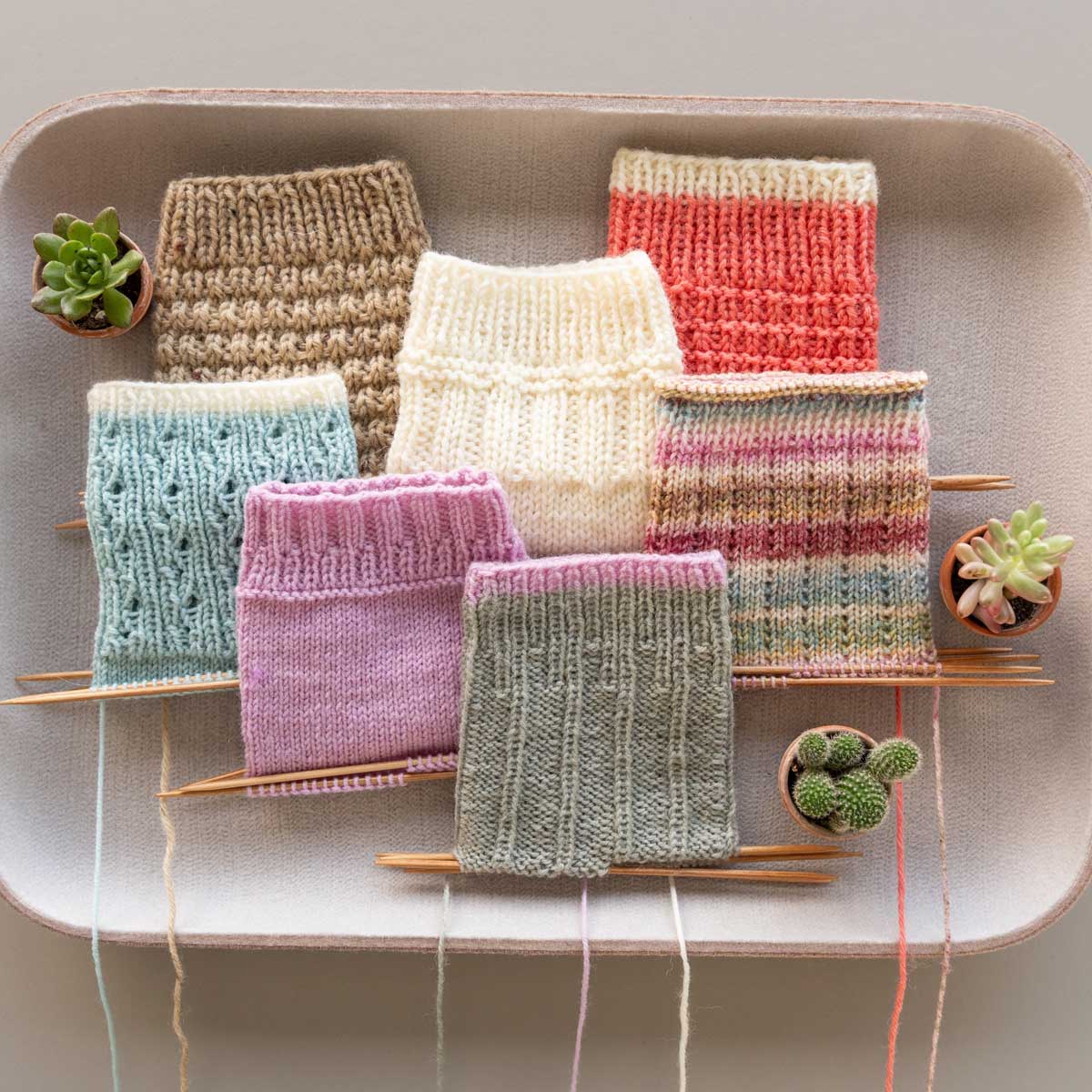 mehrere Socken auf der Nadeln mit unterschiedlichen Bundmustern und in unterschiedlichen Farben 